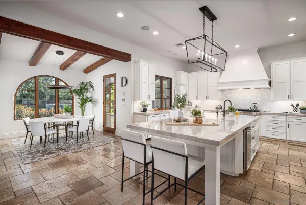 a kitchen with stainless steel appliances granite countertop a sink a stove a refrigerator and chairs