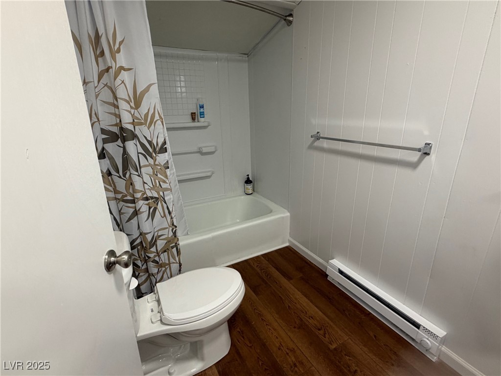 1144 Ave D Ely, NV 89301 - Photo 14 of 15 Bathroom with a baseboard heating unit, dark wood-type flooring, shower / tub combo, and wood walls