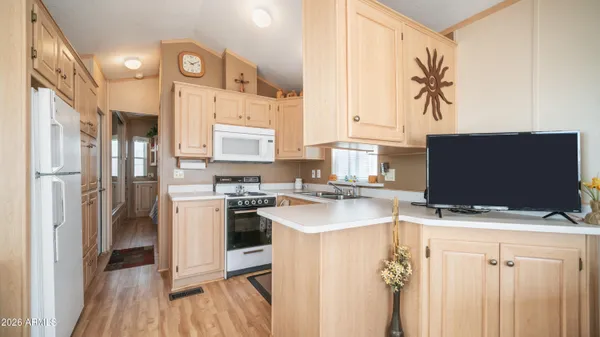 a kitchen with stainless steel appliances a stove top oven a refrigerator a sink and white cabinets with wooden floor