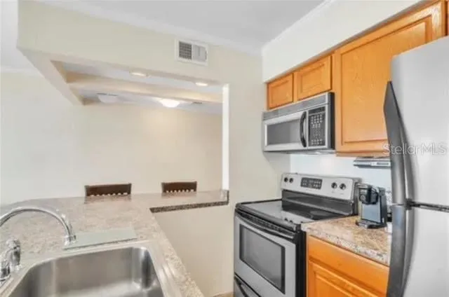 a kitchen with stainless steel appliances granite countertop a sink stove and refrigerator