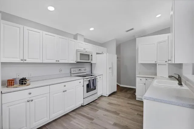 a kitchen with granite countertop white cabinets and white appliances