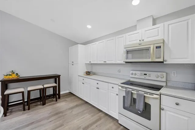a kitchen with stainless steel appliances white cabinets and wooden floor