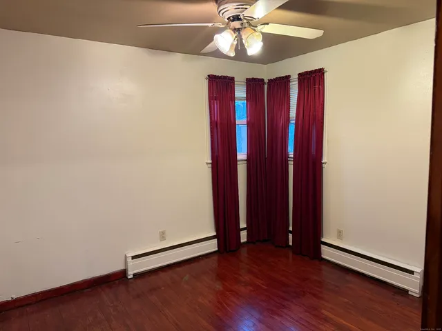 an empty room with wooden floor and fan