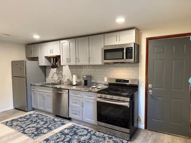 a kitchen with stainless steel appliances granite countertop a stove a refrigerator and a microwave