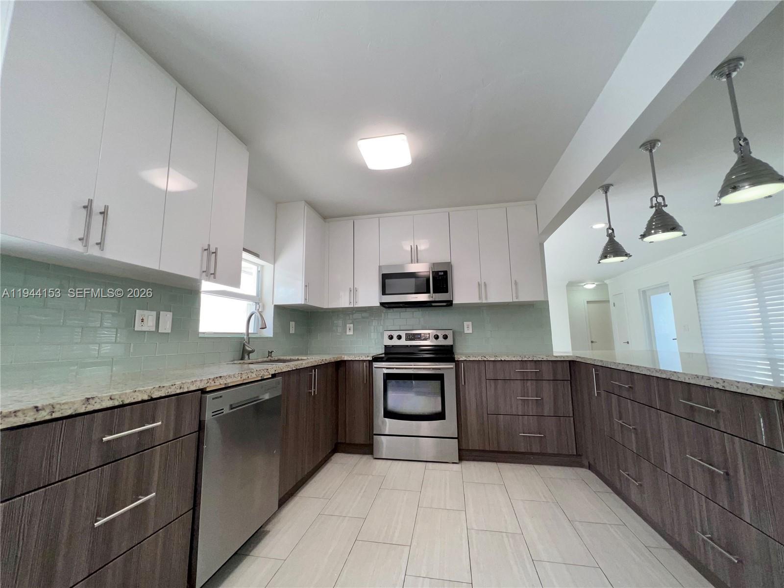 1881 Northeast 210th Street Miami, FL 33179 - Photo 21 of 29 a kitchen with stainless steel appliances granite countertop a sink counter space cabinets and a large window