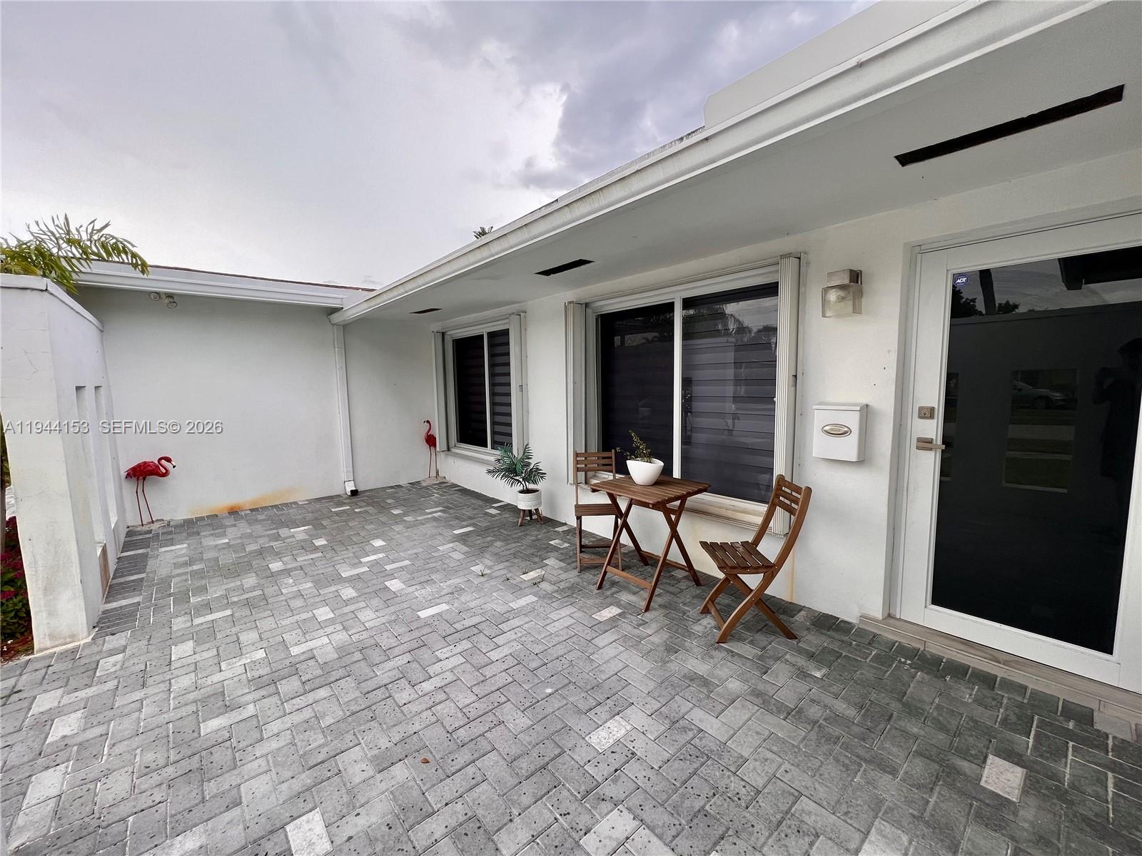 1881 Northeast 210th Street Miami, FL 33179 - Photo 22 of 29 a view of a patio with table and chairs in front of house