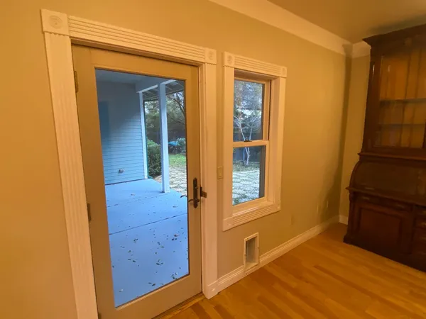 a view of an empty room with wooden floor and window