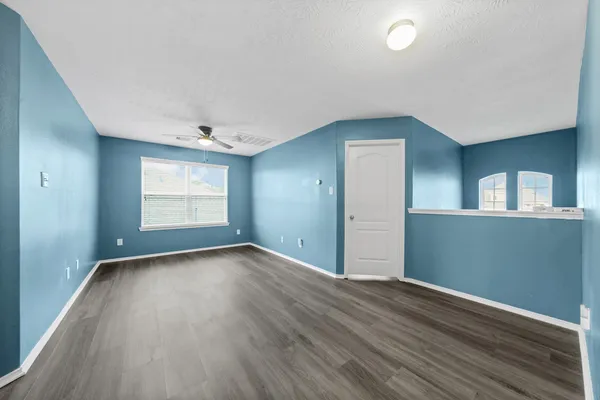 an empty room with wooden floor and windows