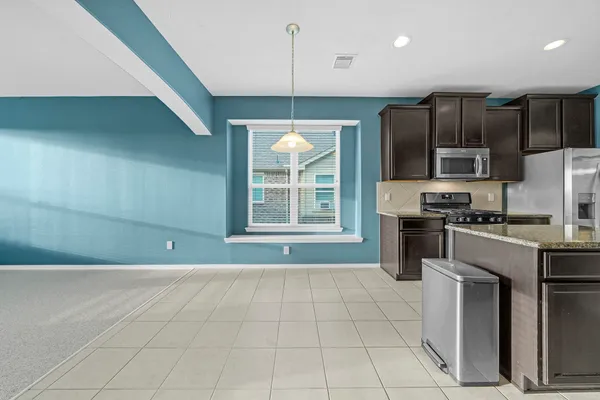 a kitchen with kitchen island granite countertop a stove a sink and a refrigerator