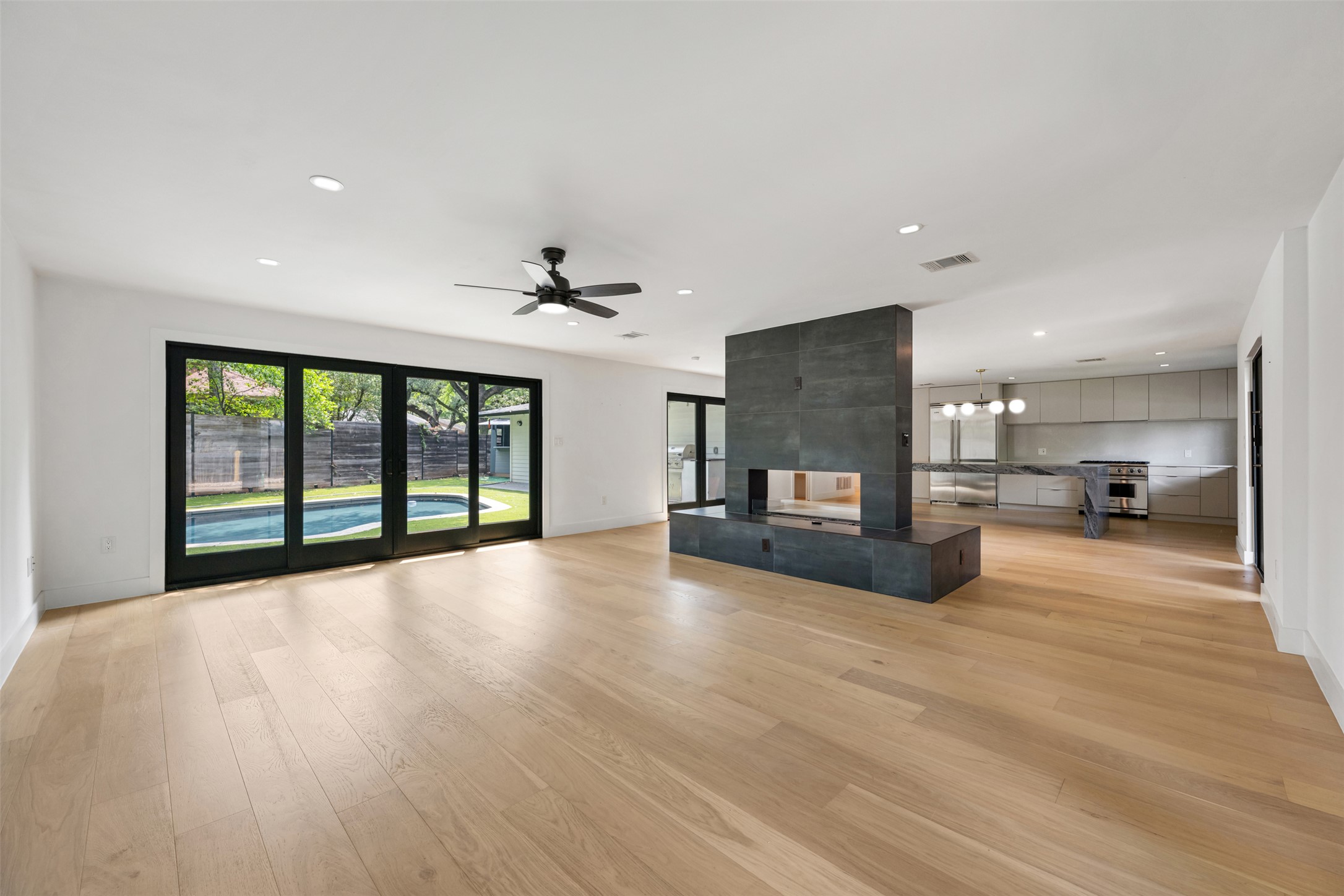 8900 Point W Drive Austin, TX 78759 - Photo 9 of 40 Bright hardwood floors and a striking fireplace anchor this open-concept living space with outdoor pool access.