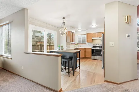 a kitchen with kitchen island granite countertop wooden cabinets and refrigerator