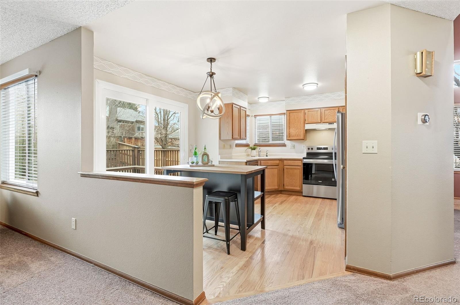 8362 Sunnyside Place Highlands Ranch, CO 80126 - Photo 14 of 50 a kitchen with kitchen island granite countertop wooden cabinets and refrigerator