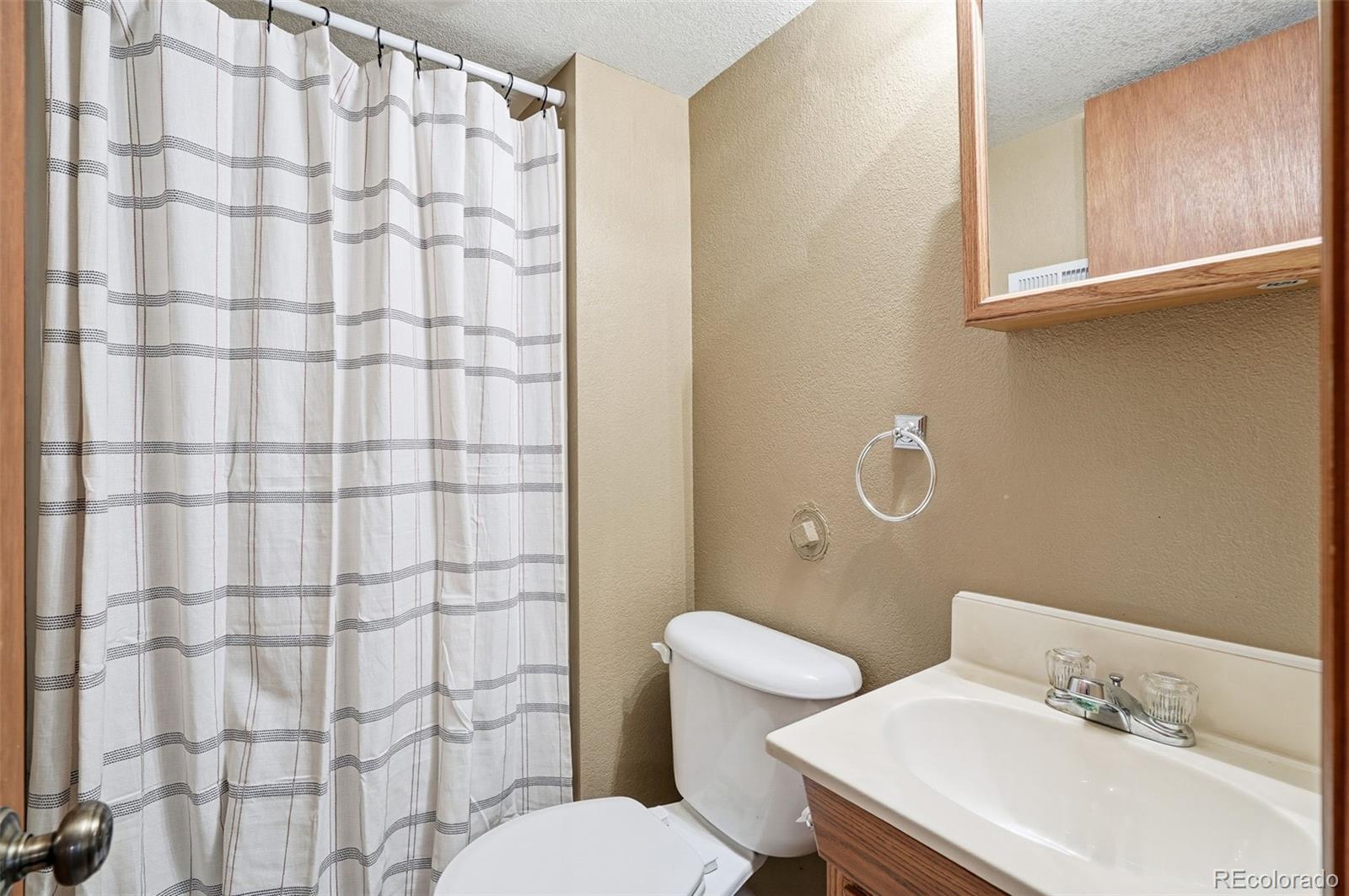 8362 Sunnyside Place Highlands Ranch, CO 80126 - Photo 44 of 50 a bathroom with a sink a toilet and shower curtain