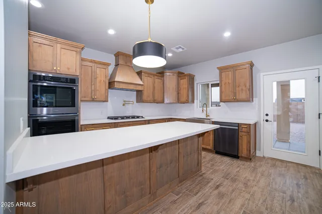 a large kitchen with a large counter top space a sink stainless steel appliances and cabinets