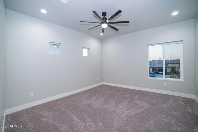 an empty room with ceiling fan and window