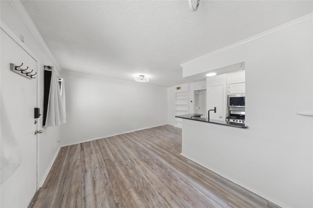 2401 Manor Road, Unit 123 Austin, TX 78722 - Photo 4 of 22 A well-lit interior features durable laminate flooring and a kitchen pass-through.