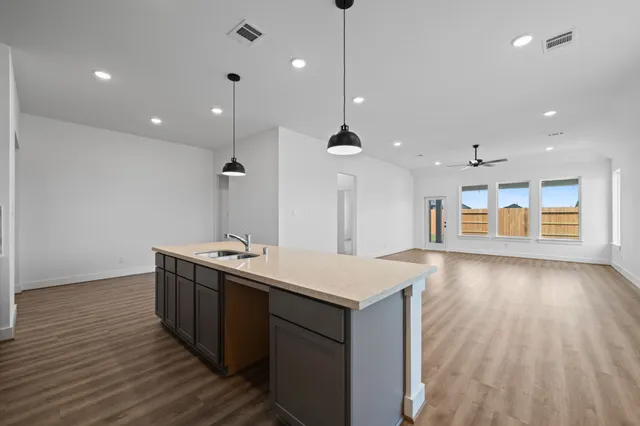 a kitchen with stainless steel appliances granite countertop a sink a stove and a wooden floors