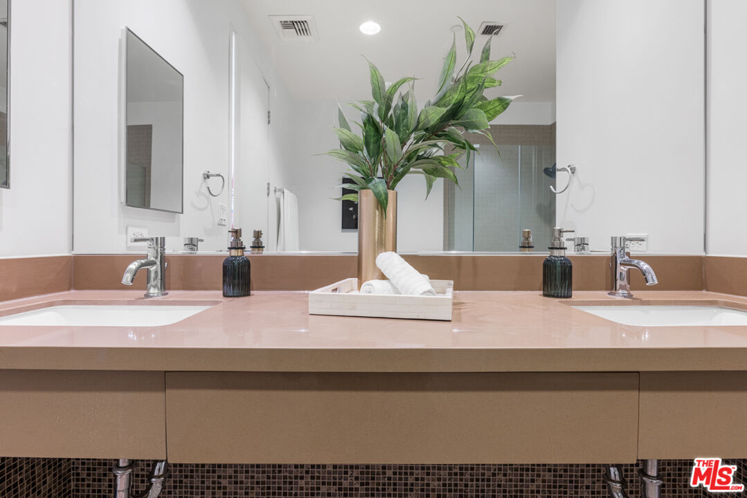 801 South Grand Avenue, Unit 1508 Los Angeles, CA 90017 - Photo 28 of 56 a bathroom with a granite countertop sink a potted plant and a mirror