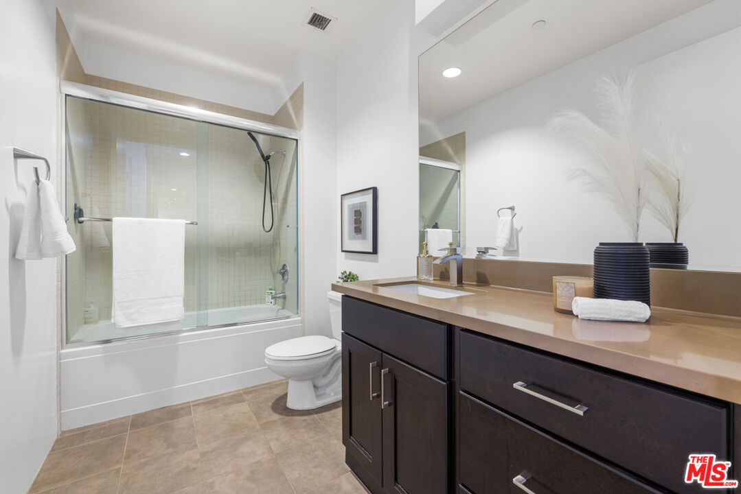 801 South Grand Avenue, Unit 1508 Los Angeles, CA 90017 - Photo 36 of 56 a bathroom with a granite countertop sink a toilet a mirror and shower