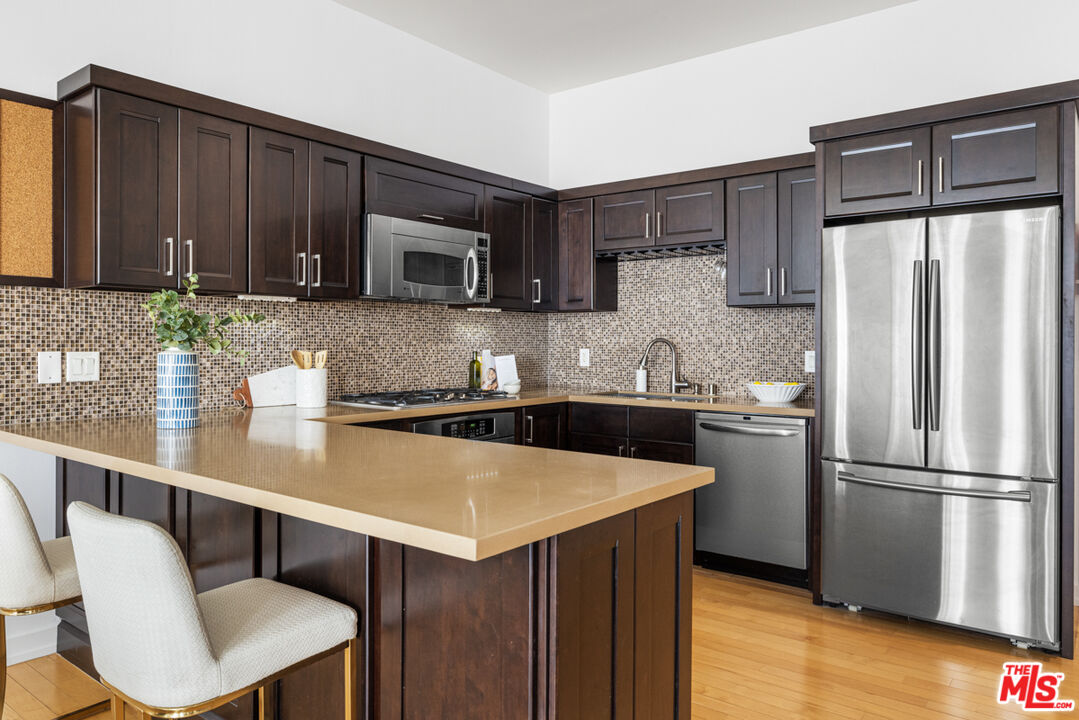 801 South Grand Avenue, Unit 1508 Los Angeles, CA 90017 - Photo 5 of 56 a kitchen with granite countertop a refrigerator stove and microwave