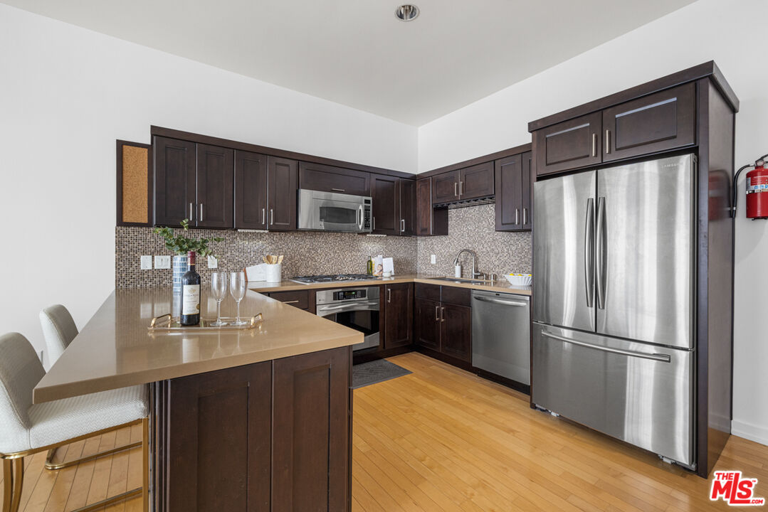 801 South Grand Avenue, Unit 1508 Los Angeles, CA 90017 - Photo 6 of 56 a kitchen with a refrigerator sink and wooden cabinets