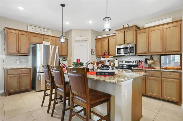 a kitchen with kitchen island granite countertop wooden cabinets and a refrigerator