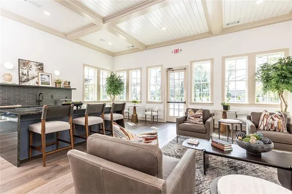 a living room with furniture large windows and wooden floor