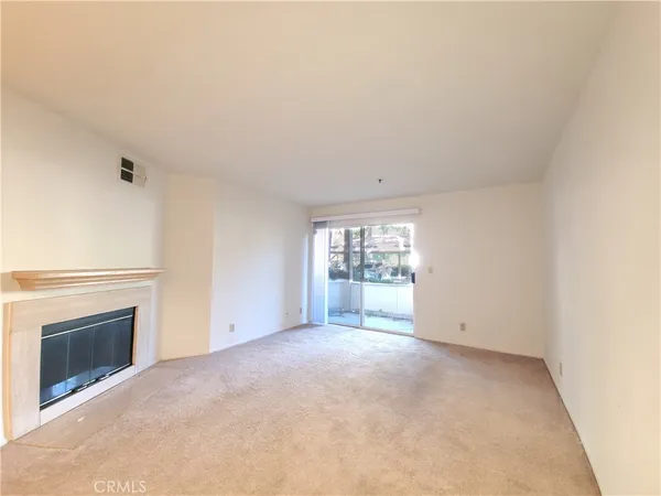 a view of an empty room with a fireplace and a window