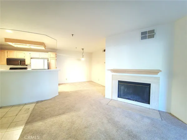 a view of a livingroom with an empty kitchen and a fireplace