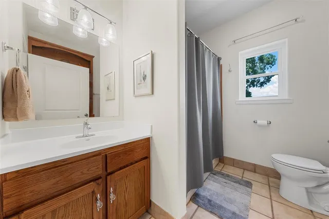 a bathroom with a granite countertop sink toilet and mirror