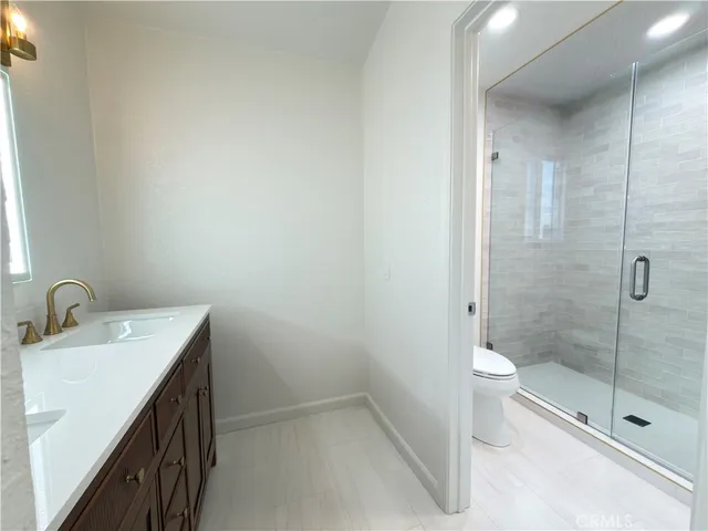 a bathroom with a granite countertop sink a toilet and shower