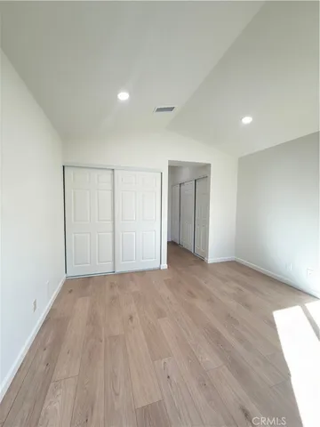 a view of an empty room with wooden floor and closet