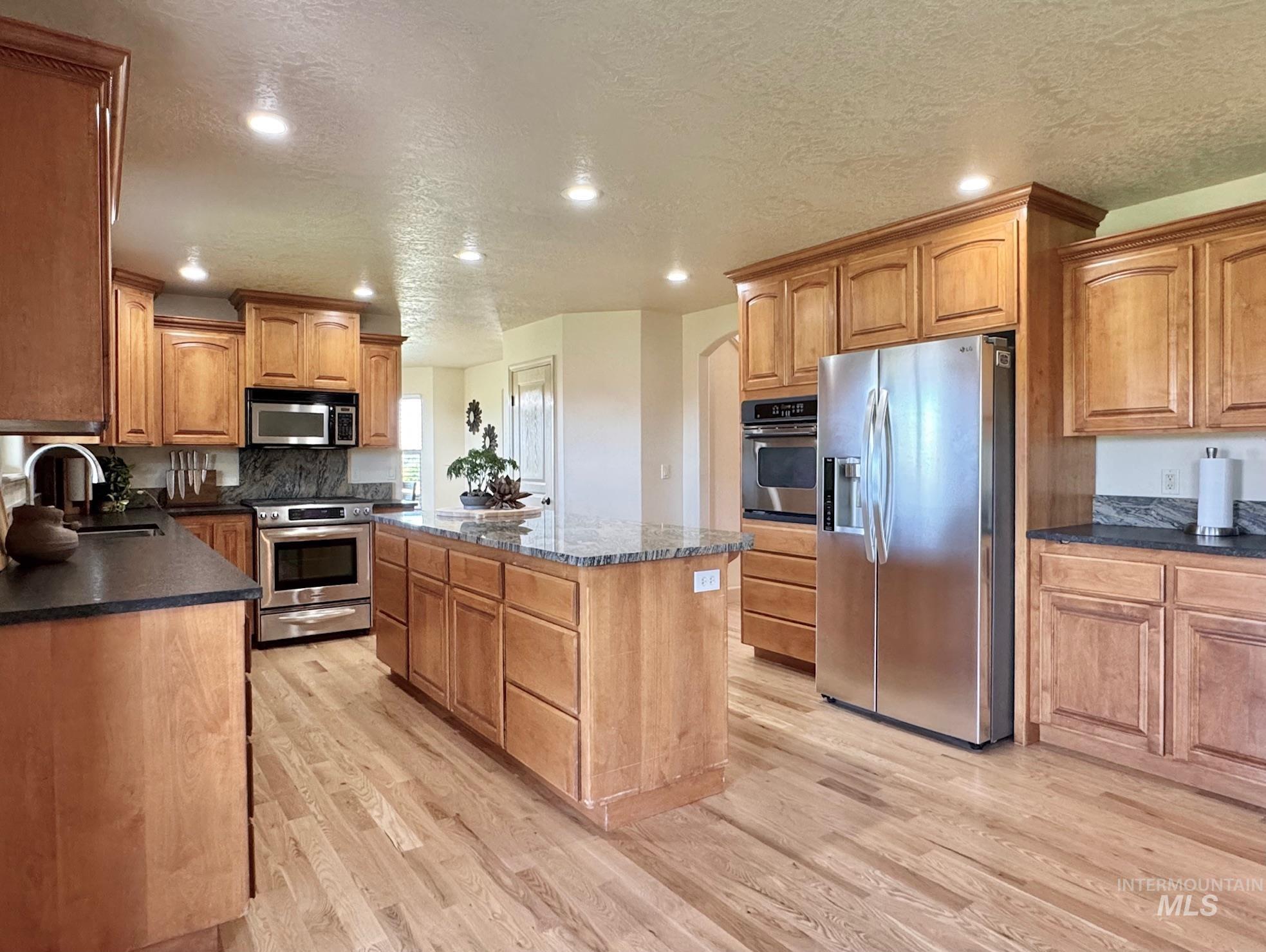9299 Kemp Road Middleton, ID 83644 - Photo 13 of 50 Spacious kitchen featuring light wood cabinetry, stainless steel appliances, and a large central island with a stone countertop