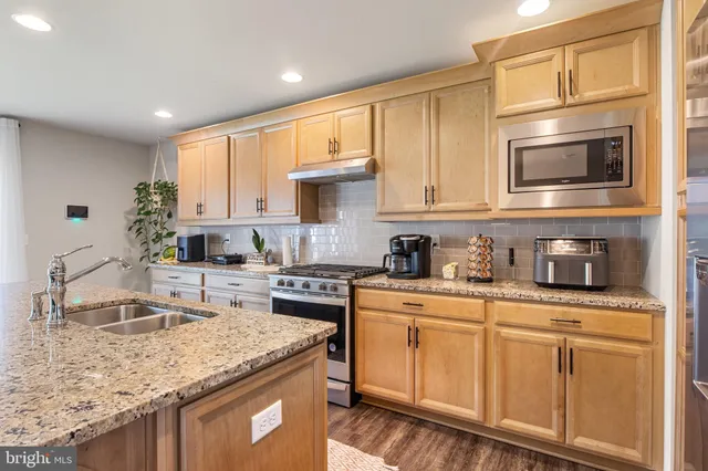a kitchen with stainless steel appliances granite countertop a sink stove and refrigerator