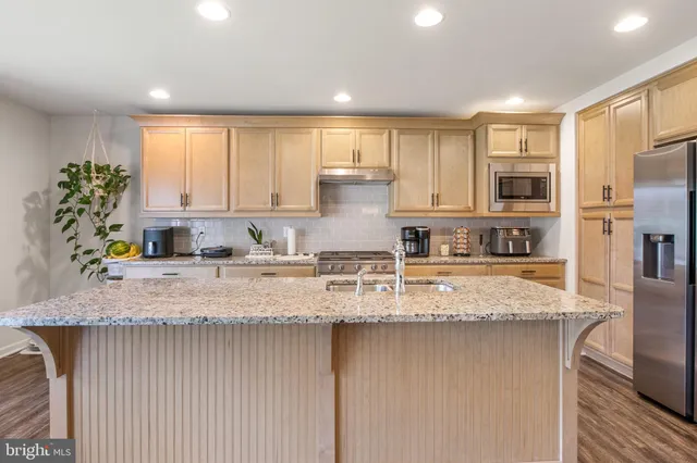 a kitchen with stainless steel appliances granite countertop a stove a sink and a refrigerator