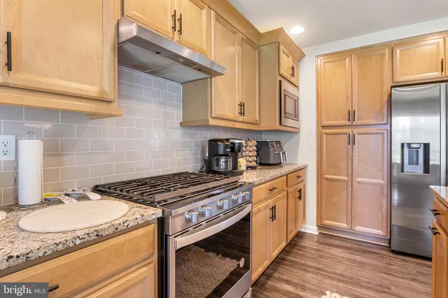 a kitchen with stainless steel appliances granite countertop a sink refrigerator and cabinets