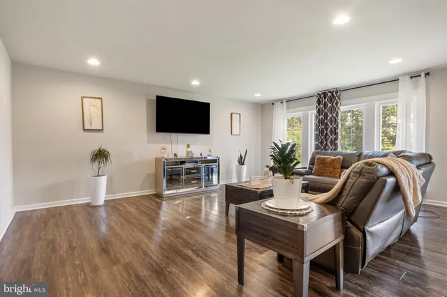a living room with furniture a flat screen tv and wooden floor