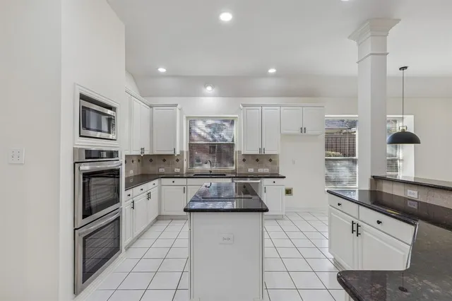a kitchen with granite countertop white cabinets and stainless steel appliances