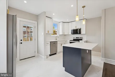 a kitchen with kitchen island white cabinets and stainless steel appliances