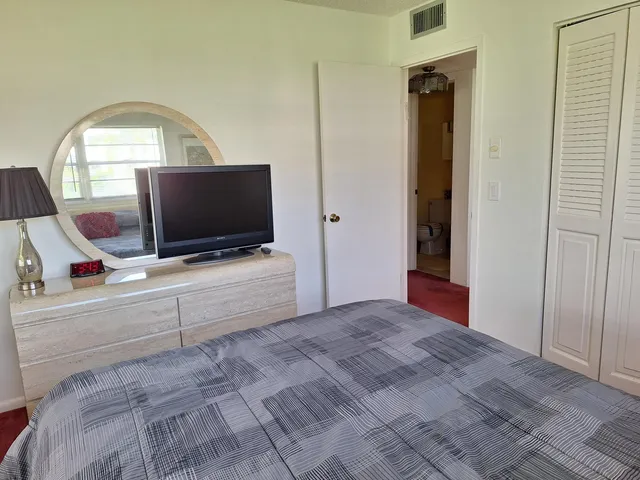 a view of an empty room with wooden floor and a flat screen tv
