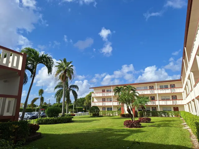 front view of a building with a big yard and potted plants