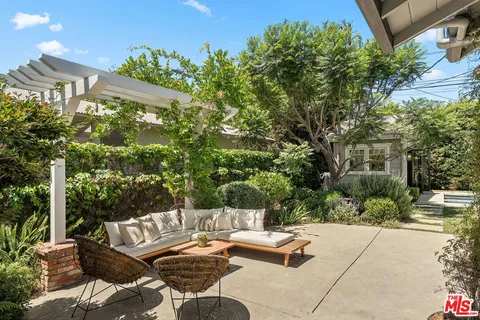 a view of a patio with couches and table and chairs with wooden fence and plants