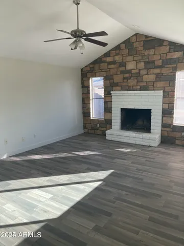 a view of an empty room with wooden floor fireplace and a window