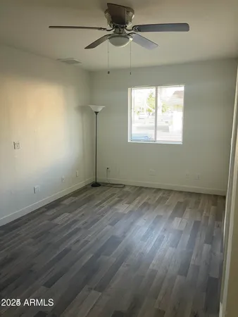 an empty room with wooden floor fan and windows