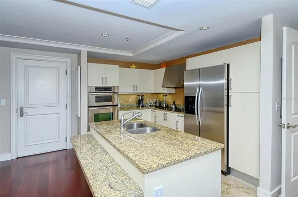 a kitchen with stainless steel appliances granite countertop sink refrigerator and cabinets