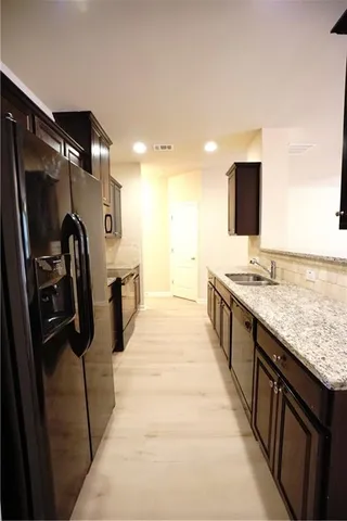 a kitchen with stainless steel appliances kitchen island granite countertop a refrigerator and a sink