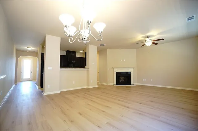 a view of an empty room with kitchen and fireplace