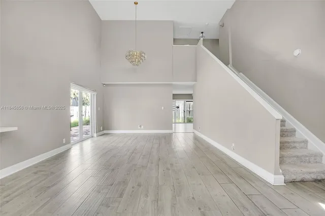 a view of an empty room with wooden floor and stairs
