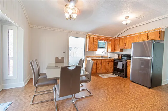 a kitchen with granite countertop a refrigerator a stove a dining table and chairs