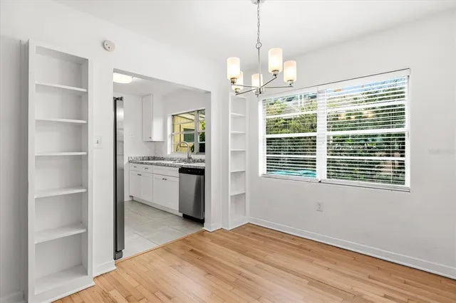 a view of an empty room with a window and kitchen view